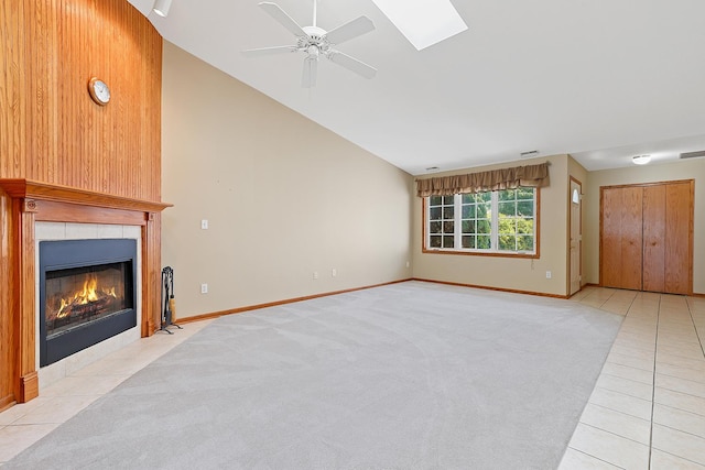 1622 Evergreen Ave, Crown Point, IN 46307 - unfurnished living room with vaulted ceiling, a tiled fireplace, ceiling fan, light tile patterned floors, and a skylight