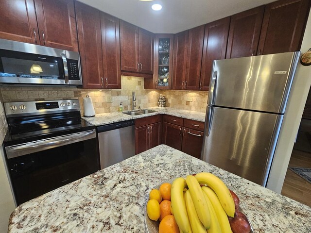 3110 Pheasant Creek Dr Unit 304, Northbrook, IL 60062 - kitchen featuring appliances with stainless steel finishes, a sink, light stone counters, glass insert cabinets, and decorative backsplash
