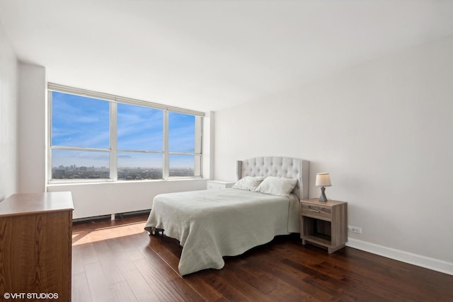 bedroom with dark wood-style flooring and baseboards