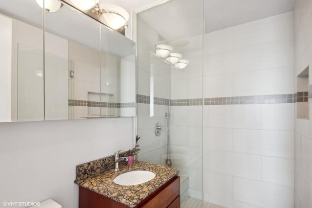 bathroom with a tile shower and vanity