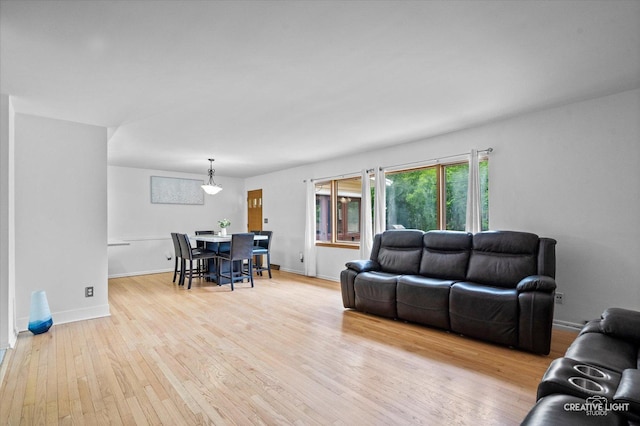 living room featuring hardwood / wood-style flooring, baseboards, and a chandelier