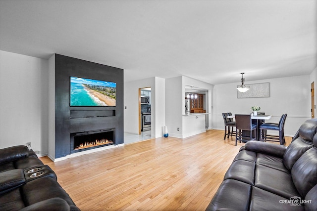 living area featuring wood finished floors, a large fireplace, and baseboards