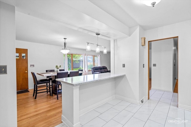 kitchen featuring hanging light fixtures, baseboards, light stone countertops, and a peninsula