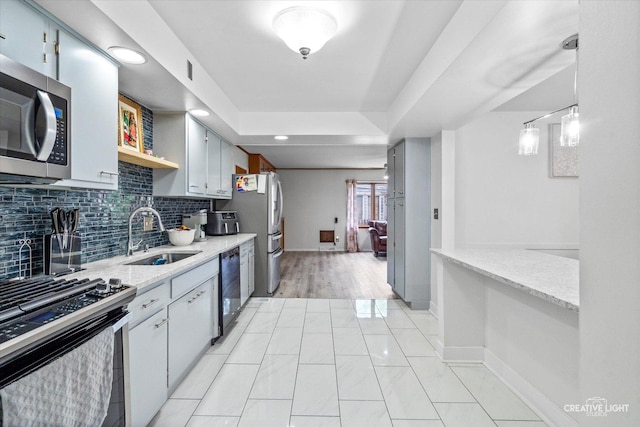 kitchen featuring a sink, appliances with stainless steel finishes, backsplash, baseboards, and light stone countertops