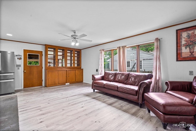 living room with ornamental molding, light wood-style flooring, and ceiling fan