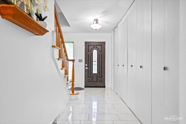 entryway with stairway, light marble finish flooring, and baseboards