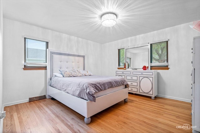 bedroom with multiple windows, baseboards, and light wood-style floors