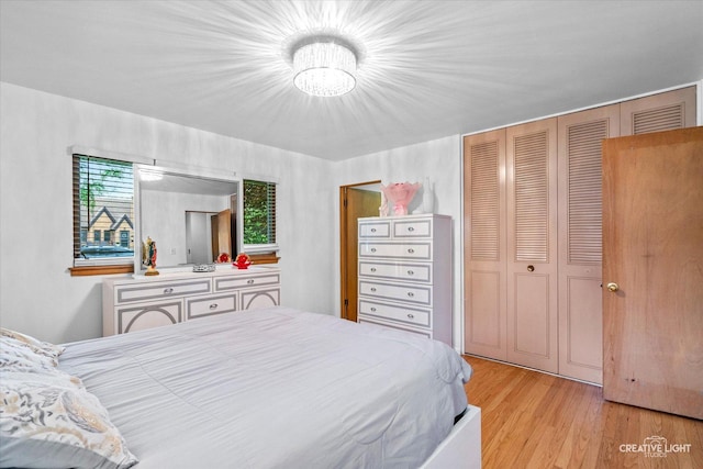 bedroom featuring light wood finished floors, a closet, and a chandelier
