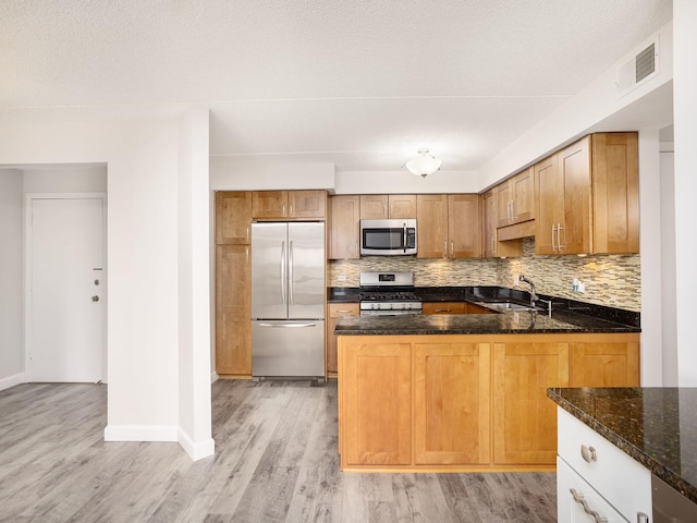 8540 W Foster Ave Unit 403, Norridge, IL 60706 - kitchen with stainless steel appliances, tasteful backsplash, dark stone countertops, light wood-type flooring, and a peninsula