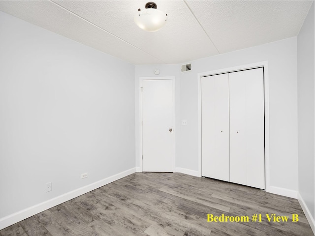 8540 W Foster Ave Unit 403, Norridge, IL 60706 - unfurnished bedroom featuring wood finished floors, baseboards, a closet, and a textured ceiling
