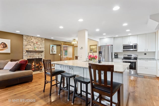 5720 Dunham Rd, Downers Grove, IL 60516 - kitchen with stainless steel appliances, a kitchen bar, light stone counters, light wood-style flooring, and recessed lighting