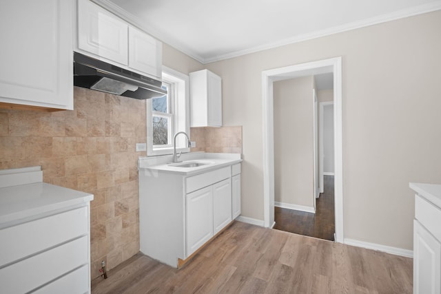 228 E 140th Pl, Dolton, IL 60419 - kitchen featuring a sink, under cabinet range hood, light countertops, white cabinets, and crown molding