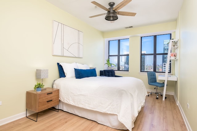 bedroom with light wood-style floors, baseboards, and ceiling fan
