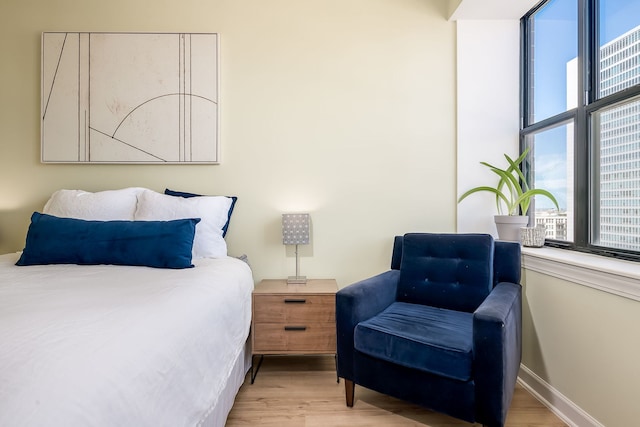 bedroom featuring multiple windows, light wood-type flooring, and baseboards