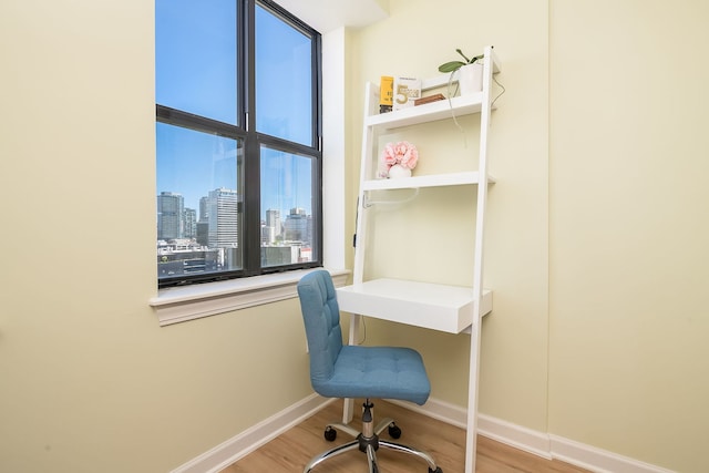 office featuring wood finished floors, baseboards, and a skyline view
