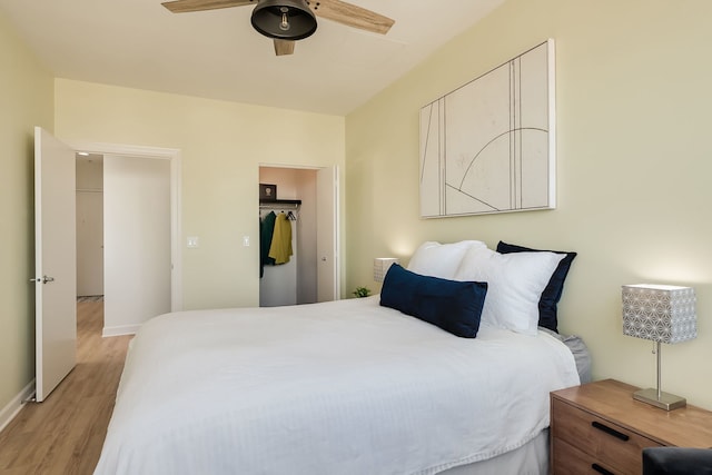 bedroom with light wood-style floors, a ceiling fan, baseboards, and a closet