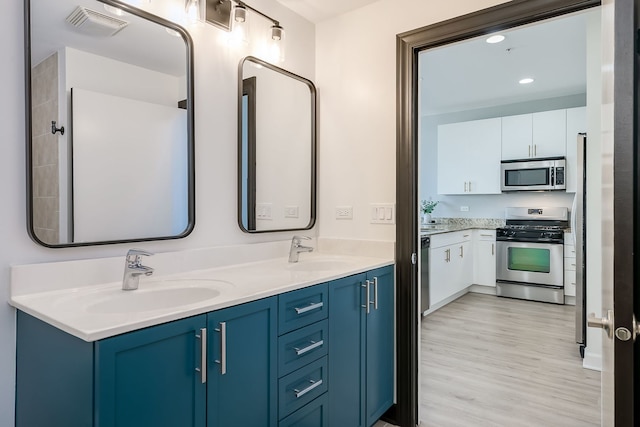 full bath with wood finished floors, double vanity, and recessed lighting