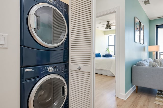 washroom with stacked washing machine and dryer, wood finished floors, baseboards, and ceiling fan