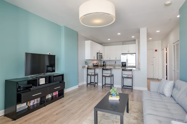 living room featuring light wood finished floors, baseboards, and recessed lighting