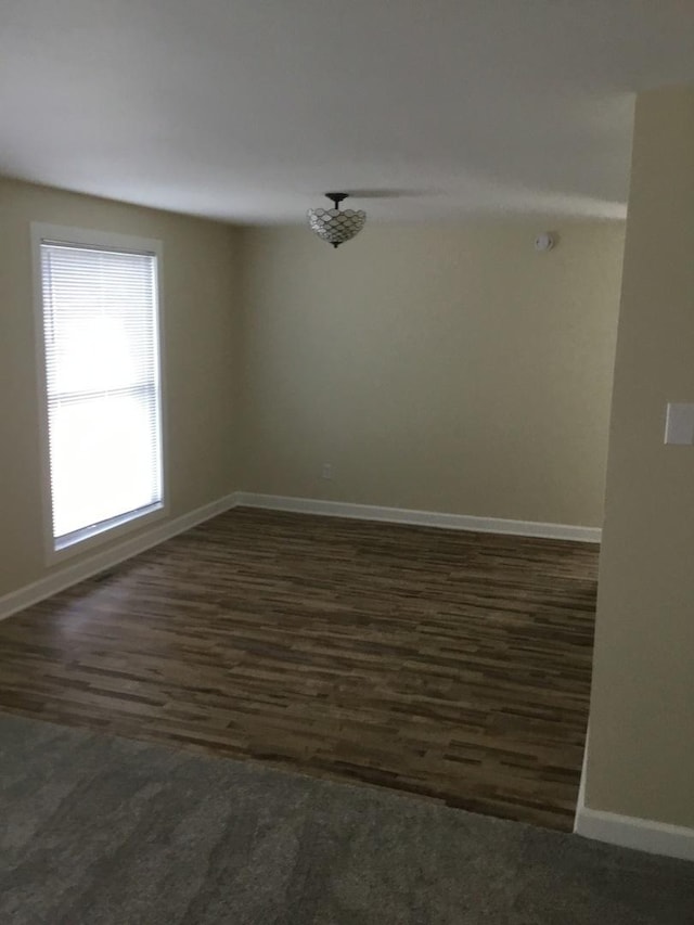 spare room featuring baseboards and dark wood-style floors