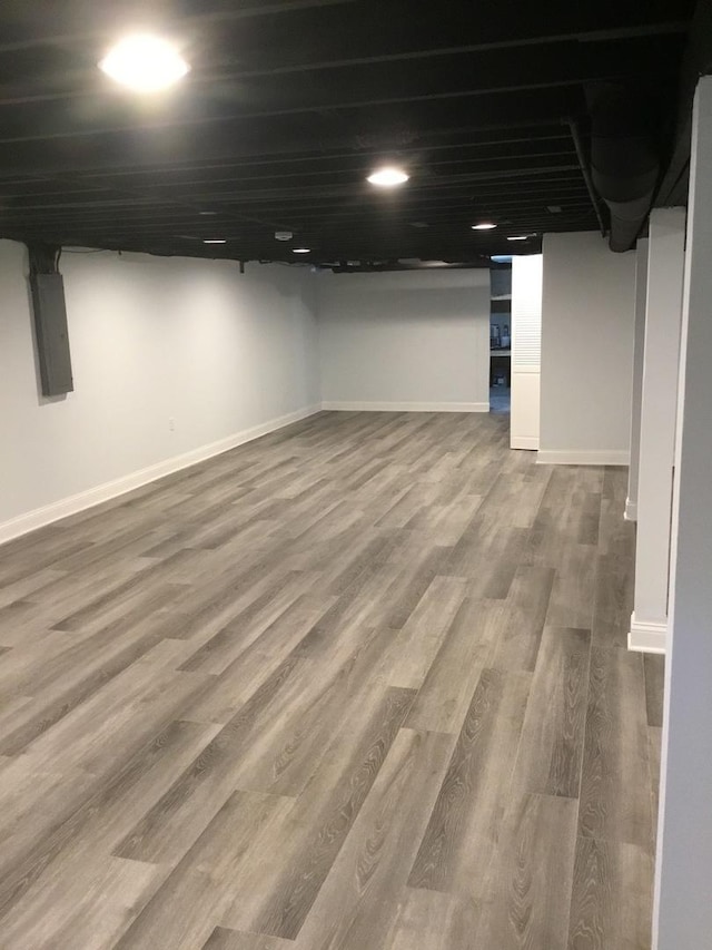 finished below grade area with electric panel, wood finished floors, and baseboards