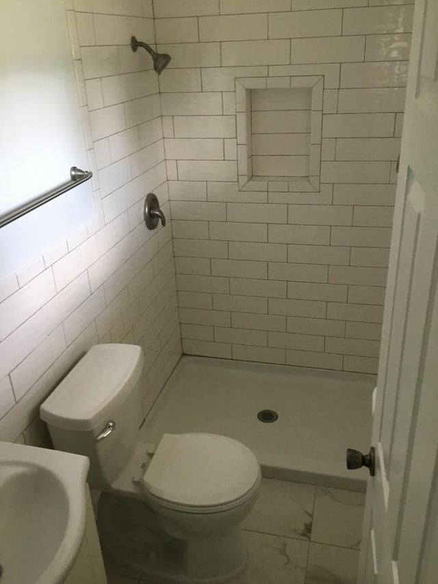 full bathroom featuring marble look tile flooring, a stall shower, and toilet