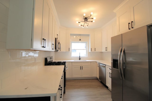 957 E Eagle St, Kankakee, IL 60901 - kitchen with appliances with stainless steel finishes, a sink, white cabinets, light countertops, and a chandelier