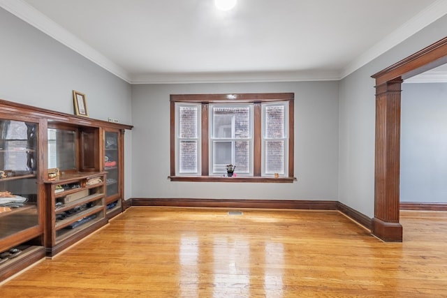 7629 S Green St, Chicago, IL 60620 - unfurnished living room featuring ornate columns, light wood-style flooring, baseboards, and crown molding