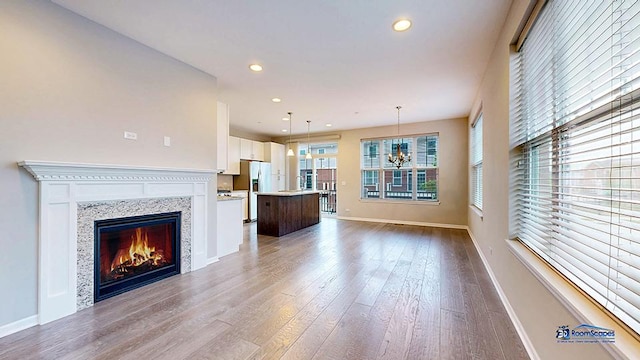 1255 Danforth Ct, Vernon Hills, IL 60061 - unfurnished living room with wood finished floors, baseboards, recessed lighting, a glass covered fireplace, and a chandelier
