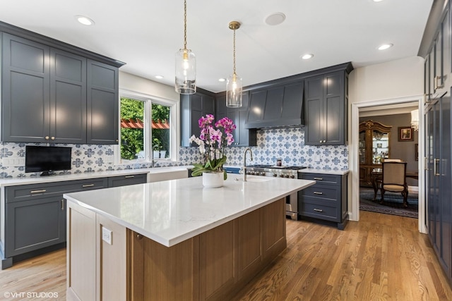 6916 Fieldstone Dr, Burr Ridge, IL 60527 - kitchen featuring stainless steel range, light wood-type flooring, custom range hood, decorative backsplash, and a kitchen island with sink