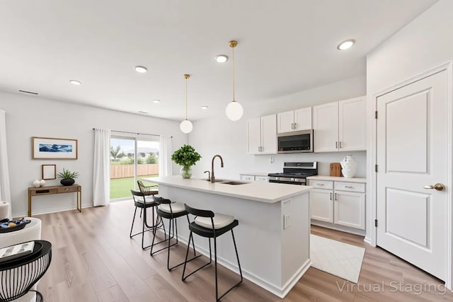 1391 Aspen Ln, Pingree Grove, IL 60140 - kitchen featuring appliances with stainless steel finishes, white cabinetry, a breakfast bar, a kitchen island with sink, and light wood-type flooring