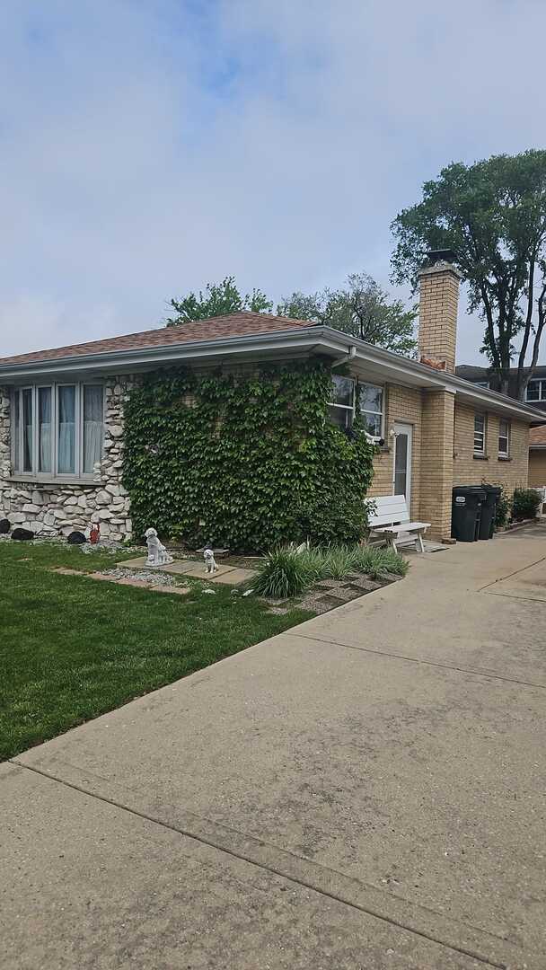 6140 Elm St, Morton Grove, IL 60053 - view of front of property with a chimney, a front lawn, concrete driveway, and stone siding