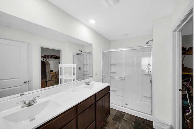 full bath with a shower stall, double vanity, and a spacious closet