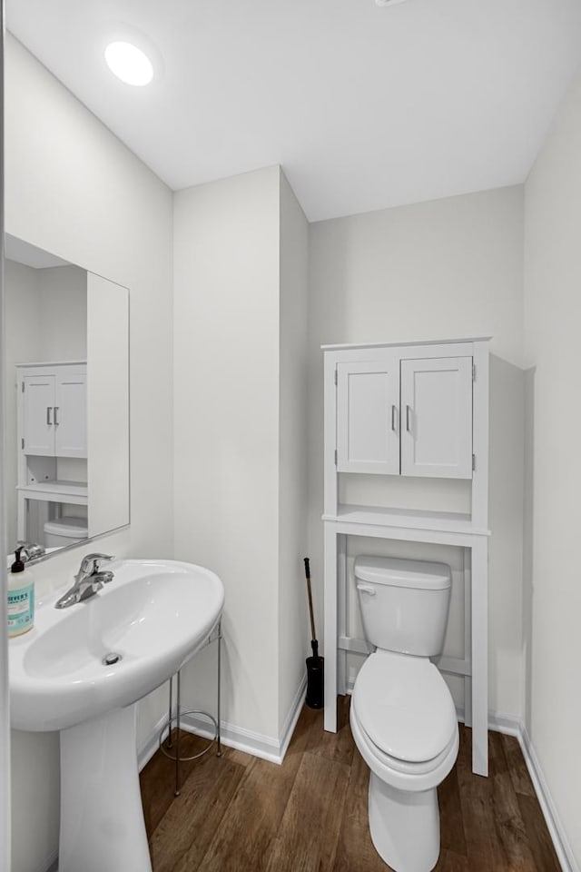 bathroom featuring toilet, wood finished floors, and baseboards