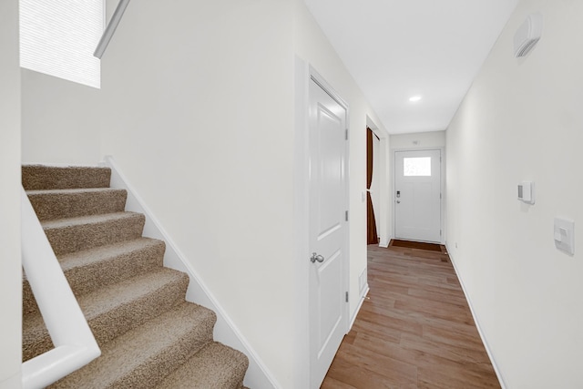 staircase featuring wood finished floors, baseboards, and recessed lighting