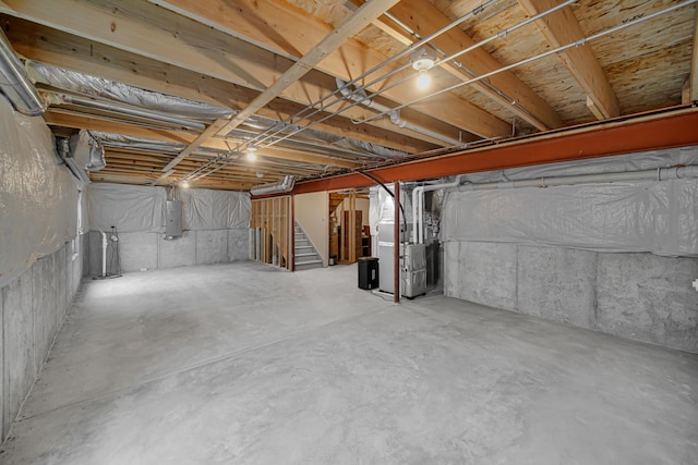 unfinished below grade area with electric panel, stairway, and heating unit