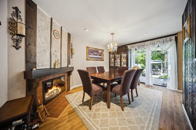 2121 Pepperwood Ln Unit 0, Glendale Heights, IL 60139 - dining space with a chandelier, a fireplace with flush hearth, light wood-style floors, and baseboards