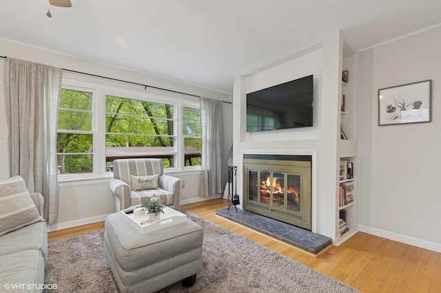 431 Elm Ave, Geneva, IL 60134 - living room featuring ornamental molding, baseboards, a glass covered fireplace, built in features, and wood finished floors
