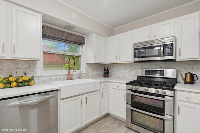 431 Elm Ave, Geneva, IL 60134 - kitchen featuring stainless steel appliances, light countertops, ornamental molding, white cabinetry, and light wood-style flooring