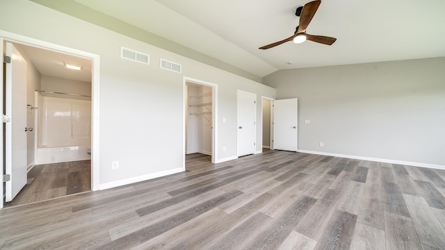 677 Southtowne Dr Unit 1, Belvidere, IL 61008 - unfurnished bedroom with wood finished floors, lofted ceiling, baseboards, connected bathroom, and a spacious closet