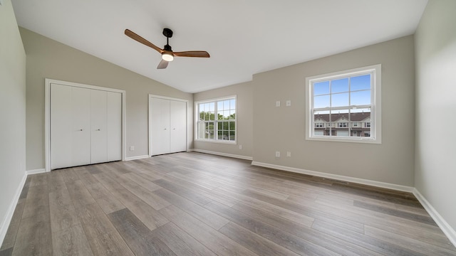 677 Southtowne Dr Unit 1, Belvidere, IL 61008 - unfurnished bedroom with two closets, wood finished floors, lofted ceiling, and baseboards