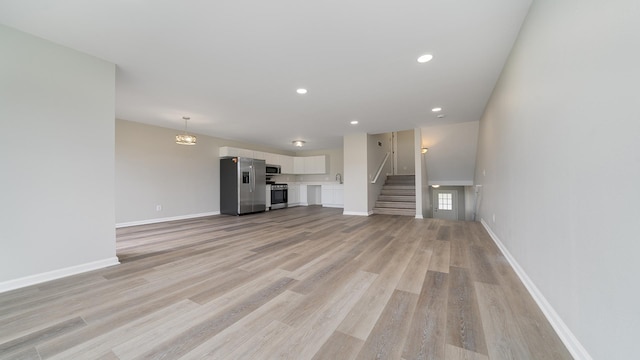 677 Southtowne Dr Unit 1, Belvidere, IL 61008 - unfurnished living room featuring light wood-style flooring, stairway, baseboards, and recessed lighting