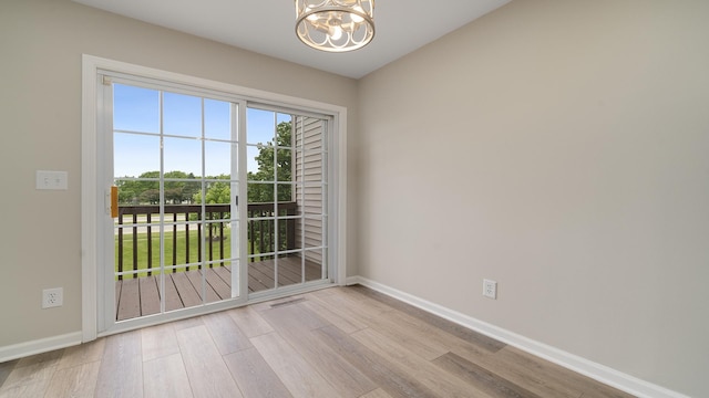 677 Southtowne Dr Unit 1, Belvidere, IL 61008 - empty room with a chandelier, wood finished floors, and baseboards