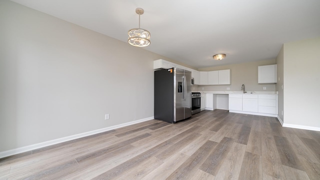 677 Southtowne Dr Unit 1, Belvidere, IL 61008 - kitchen with stainless steel appliances, light countertops, light wood-type flooring, white cabinets, and baseboards