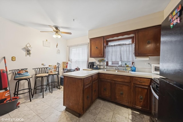 5351 N Kimball Ave, Chicago, IL 60625 - kitchen with freestanding refrigerator, a sink, a peninsula, ceiling fan, and light countertops