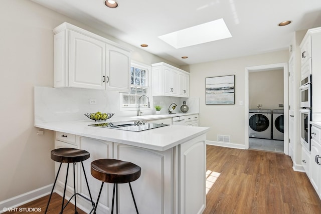 2028 Creekside Dr, Wheaton, IL 60189 - kitchen with washing machine and dryer, a sink, a skylight, a peninsula, and black electric cooktop