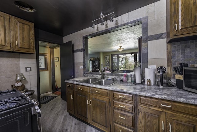 1311 Eastview Dr, Waukegan, IL 60085 - kitchen with a sink, tile walls, black range with gas cooktop, wood finished floors, and decorative backsplash
