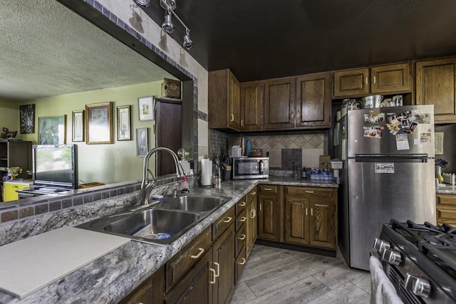 1311 Eastview Dr, Waukegan, IL 60085 - kitchen with a sink, stainless steel appliances, a textured ceiling, decorative backsplash, and light wood finished floors
