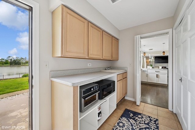 4141 Rutgers Ln, Northbrook, IL 60062 - kitchen featuring light countertops, light brown cabinets, black microwave, light tile patterned floors, and a water view
