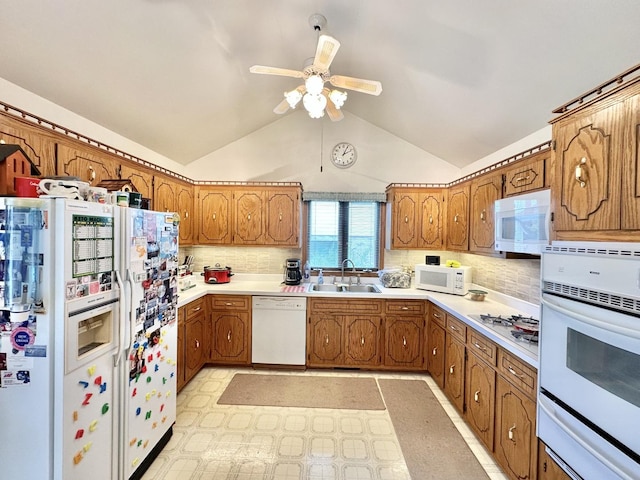 kitchen with white appliances, a sink, brown cabinetry, a warming drawer, and vaulted ceiling